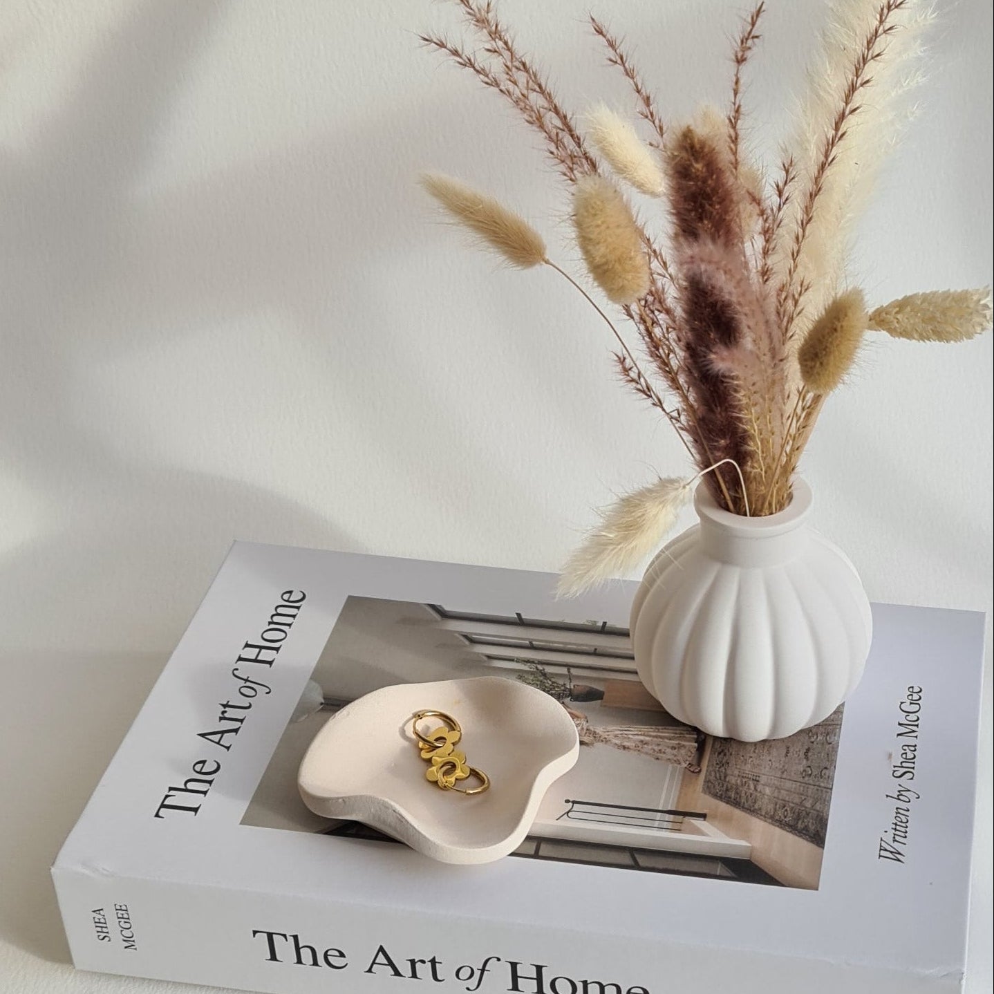 Petal dish and Lyra vase in natural lighting, on a book called 'The Art of Home'