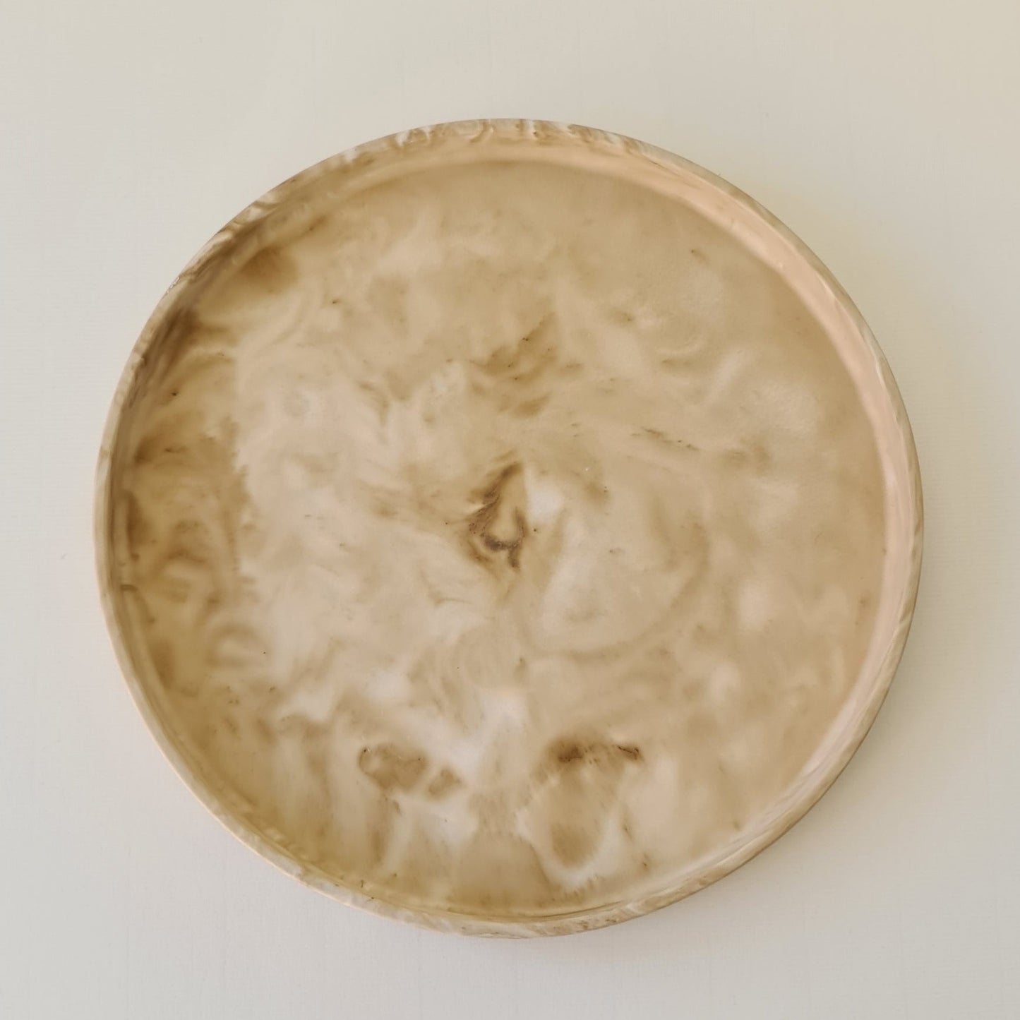 Round marbled tray with a smooth surface on a light beige background