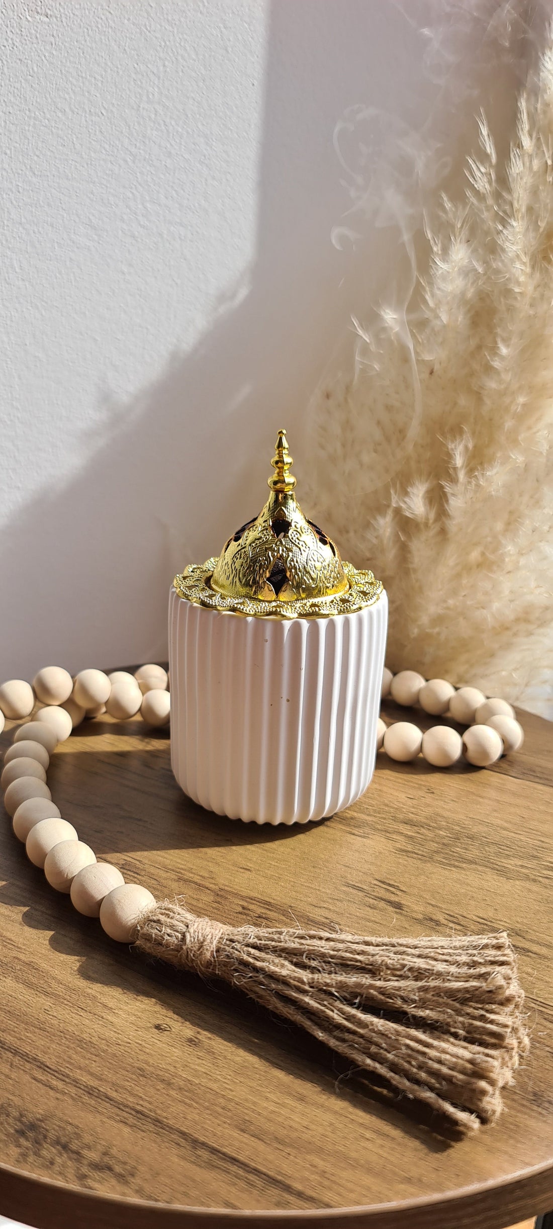 Sahar Bukhoor Burner on a small side table. Sahar carries the spirit of eastern heritage in every curve. Its ribbed base cradles a golden filigree dome - a nod to the ornate beauty found in Middle Eastern metalwork.