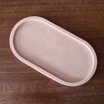pale brown oval trinket tray on wooden surface.