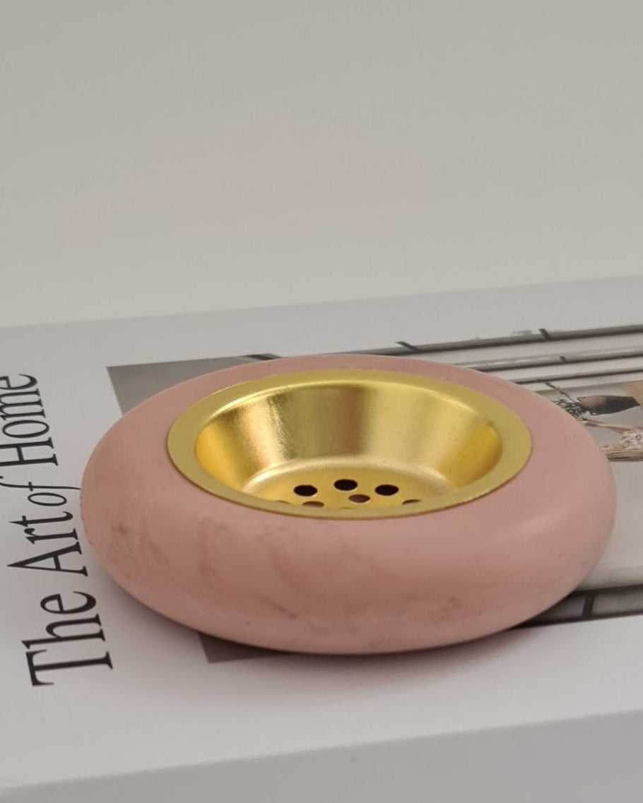Dusty rose incense holder with gold interior on a magazine