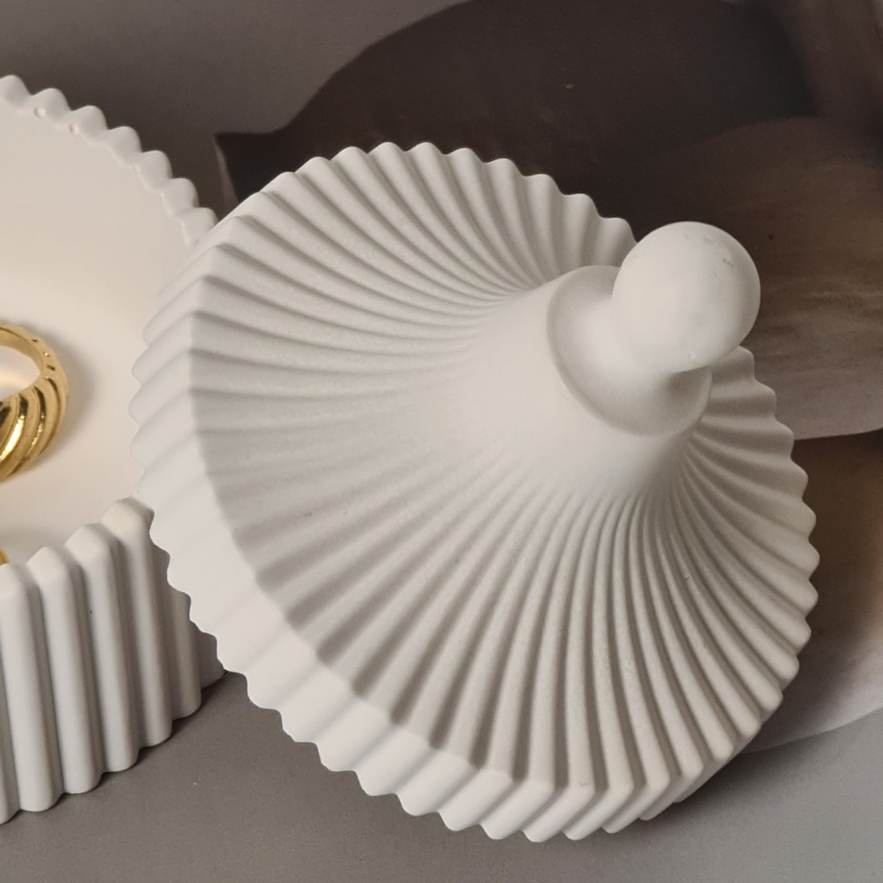 White decorative jar and lid with a textured design on a light gray background