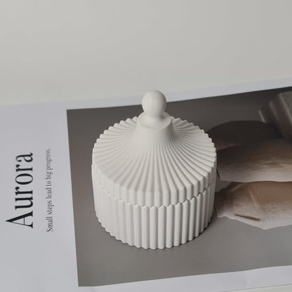 Decorative lidded jar with 'Aurora' magazine on a white background