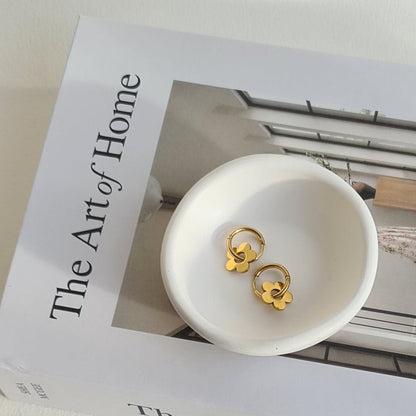 Small white dish with gold earrings on a box labeled 'The Art of Home'.