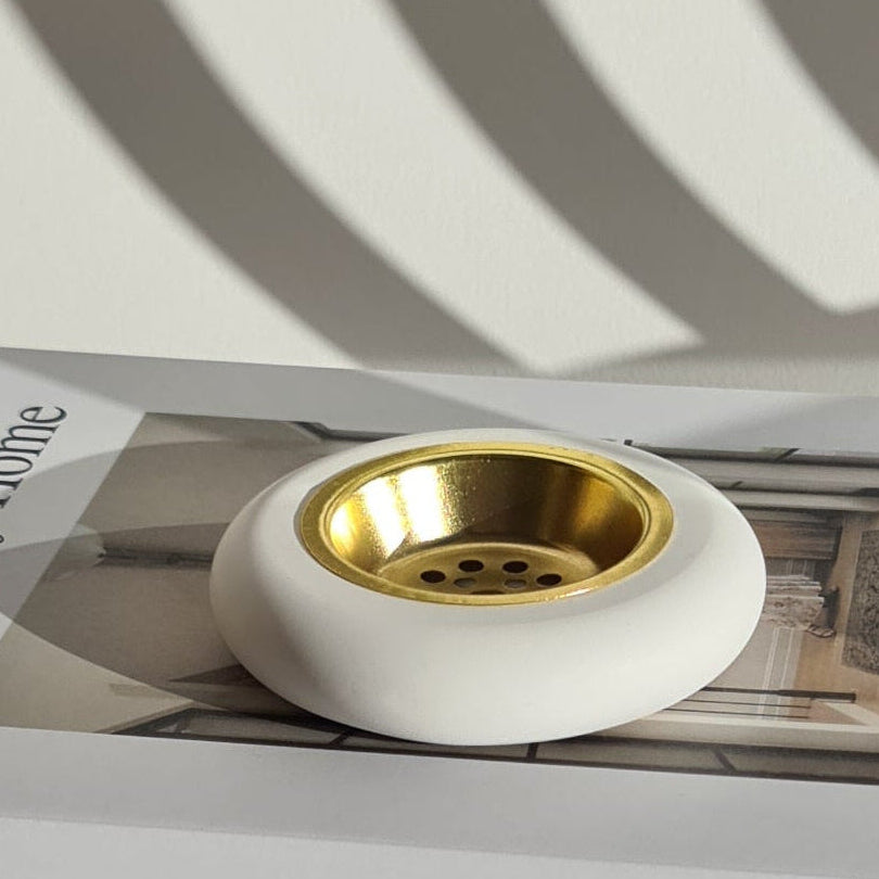 White and mordern bukhoor burner with gold metal plate on a book