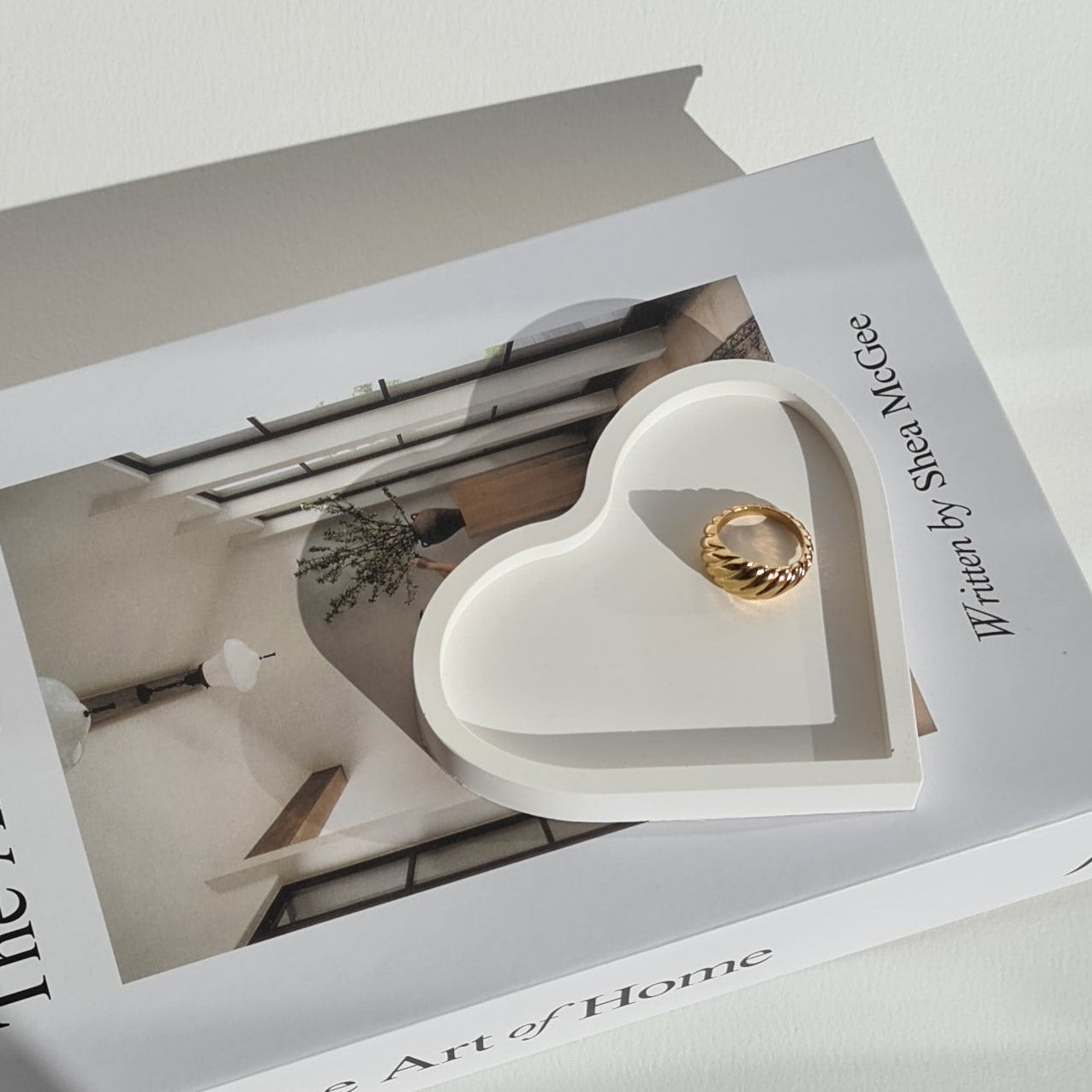 Heart-shaped dish on book titled 'The Art of Home' on a white surface