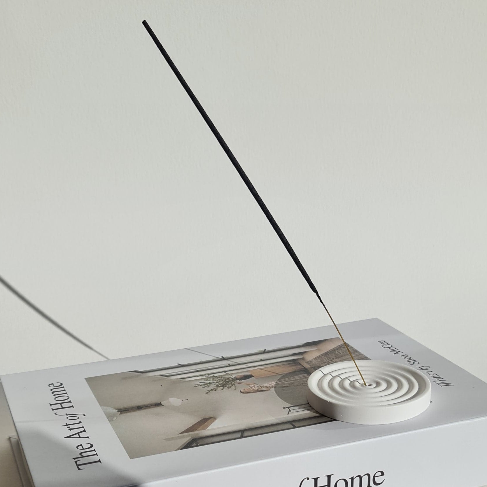 Incense holder on 'The Art of Home' book on a white surface.