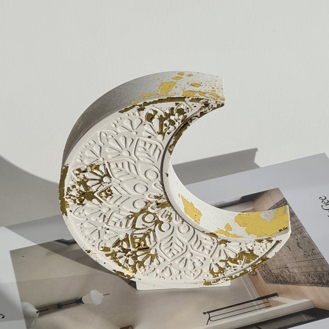 Decorative crescent moon ornament with gold patterns on a magazine