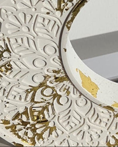 Decorative half-moon sculpture with gold and white patterns on a light background