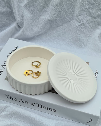 Wasl natural white jewelry jar with gold earrings on a book titled 'The Art of Home' in natural light.
