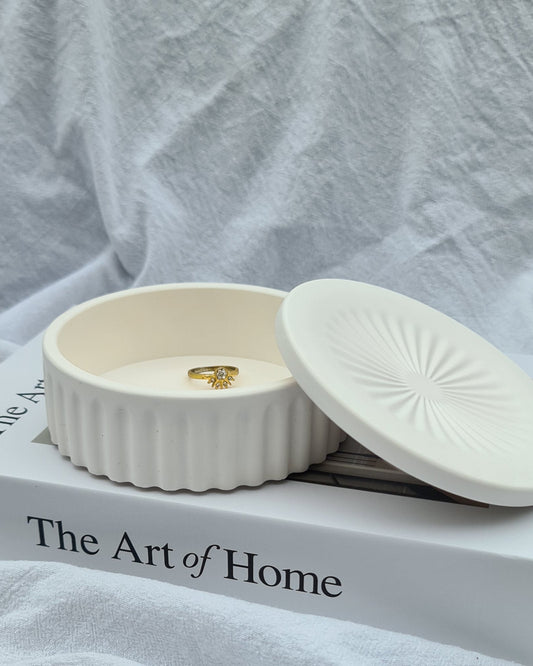 Natural white Wasl jar bowl with a gold ring on a white fabric background with 'The Art of Home' book.