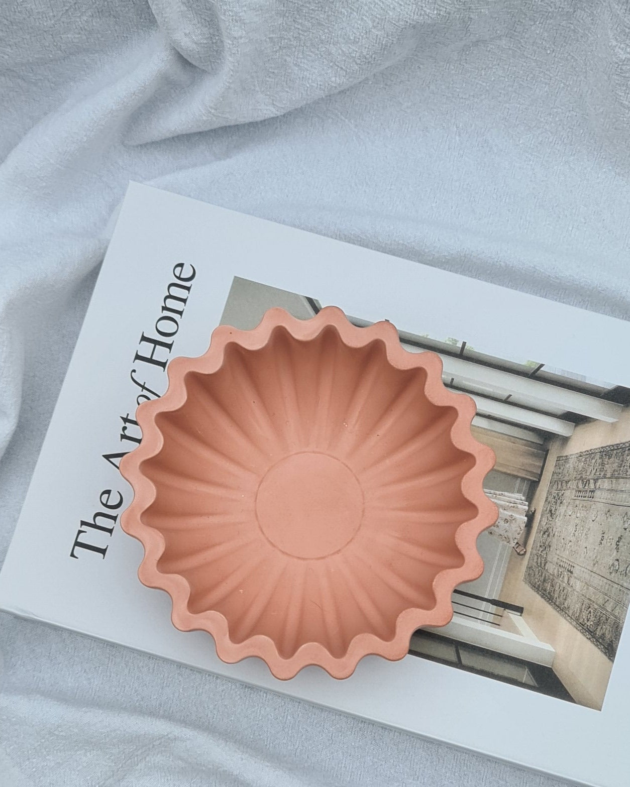 Fluted bowl Maari with 'The Art of Home' book on a textured surface
