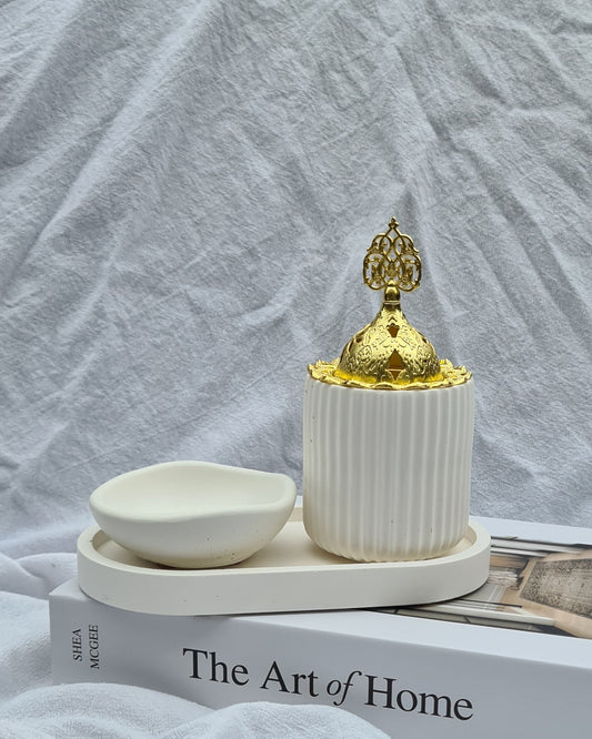Handcrafted white ceramic incense burner with gold dome lid and matching dish on a neutral tray — MINKO HOME Raayah Set styled on The Art of Home book.