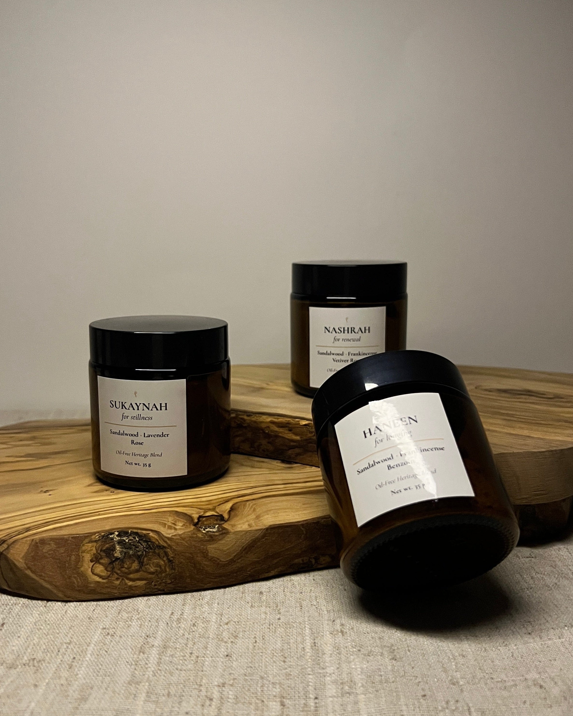 three oil-free bukhoor, three scents, three blends, on wooden board, with natural background