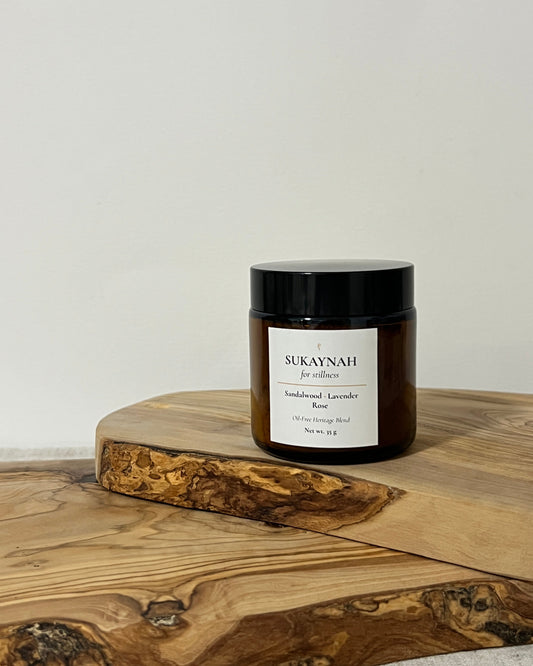 Amber jar of oil-free bukhoor on a wooden board with a neutral background