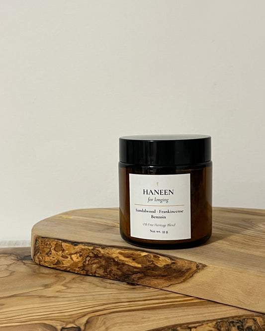 Amber jar of oil-free bukhoor on a wooden surface and white background