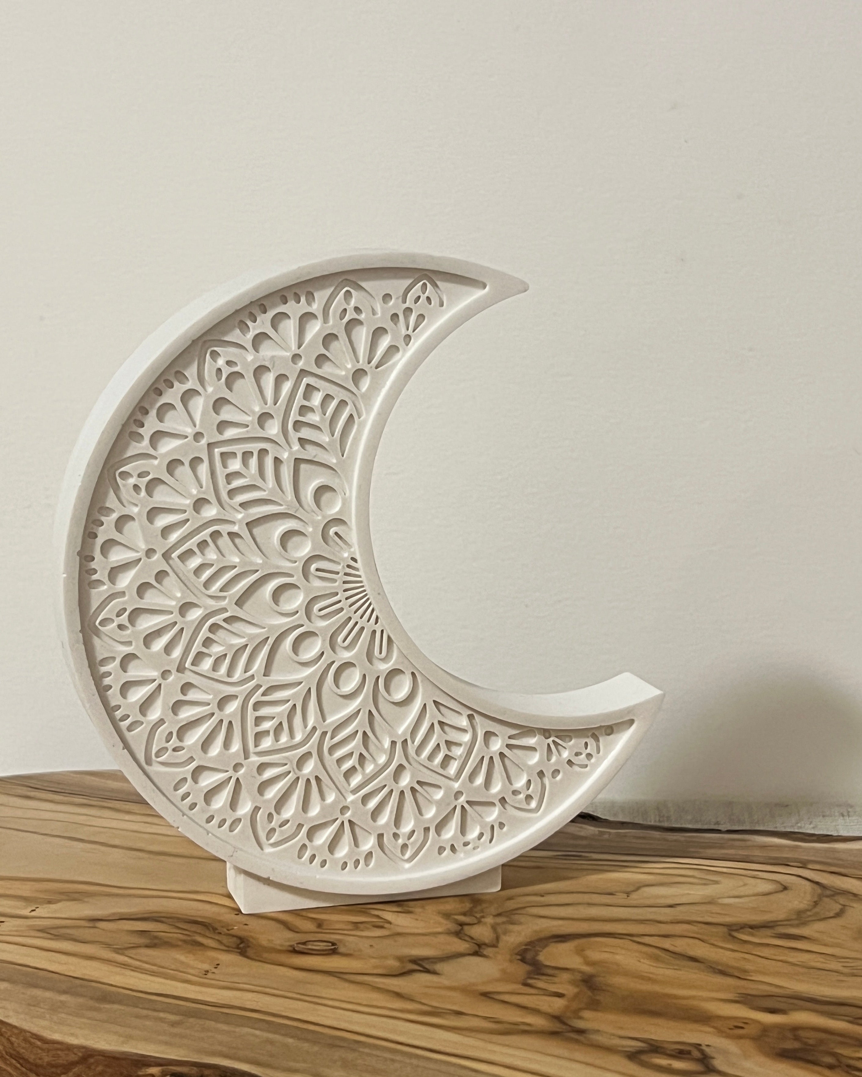 a sculptural crescent moon decoration piece on wooden board