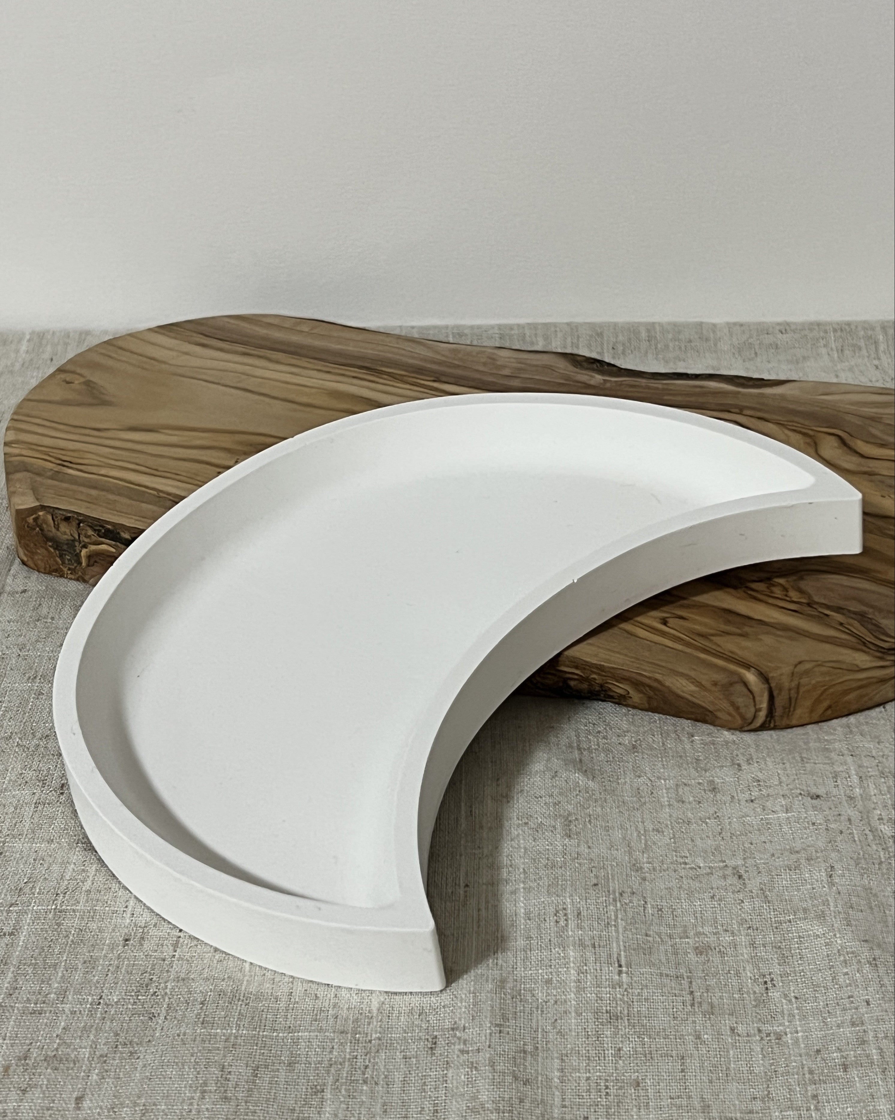 White crescent decorative tray on a wooden surface with a neutral background